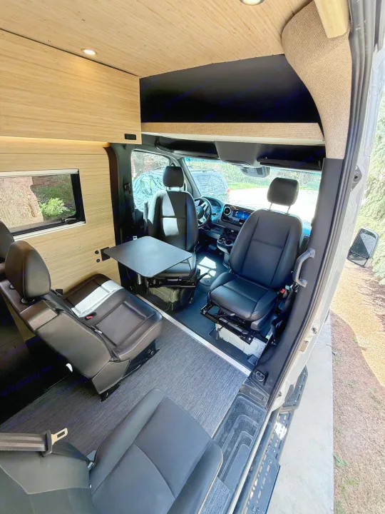 RV rental camper van interior: Swivel seats, dining table, and cozy wood paneling offer a comfy mobile living space.. Mercedes-Benz Sprinter 2024