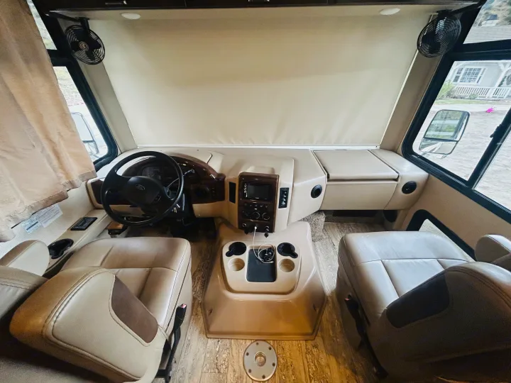 Spacious RV rental cockpit featuring driver and passenger seats, dashboard controls, and convenient fans.. Thor Hurricane 2018