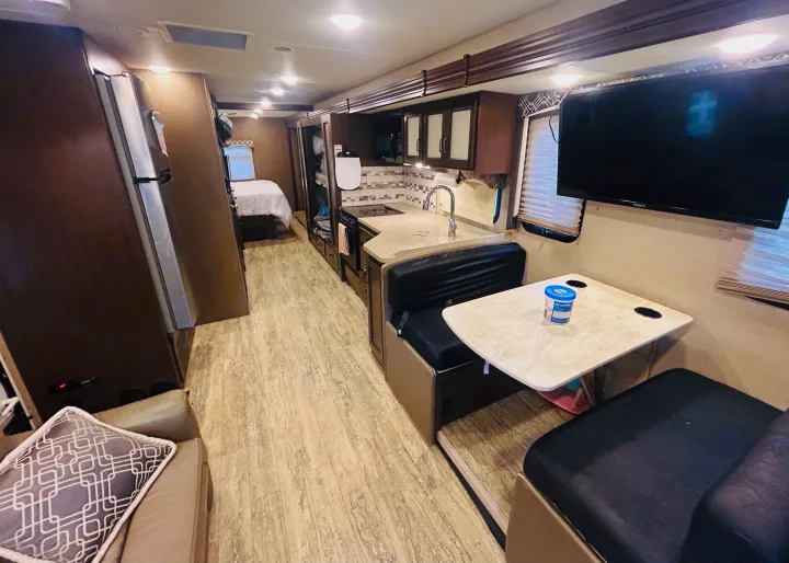 Spacious RV rental interior featuring a kitchen, dinette, living area, and a bedroom further inside.. Thor Hurricane 2018