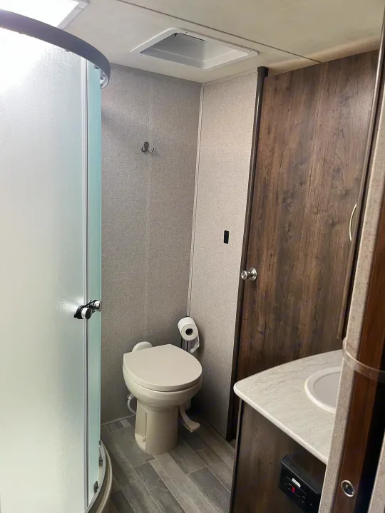 An RV rental's compact bathroom, featuring a shower, toilet, and sink, perfect for your next trip.. Dutchmen Astoria 2018