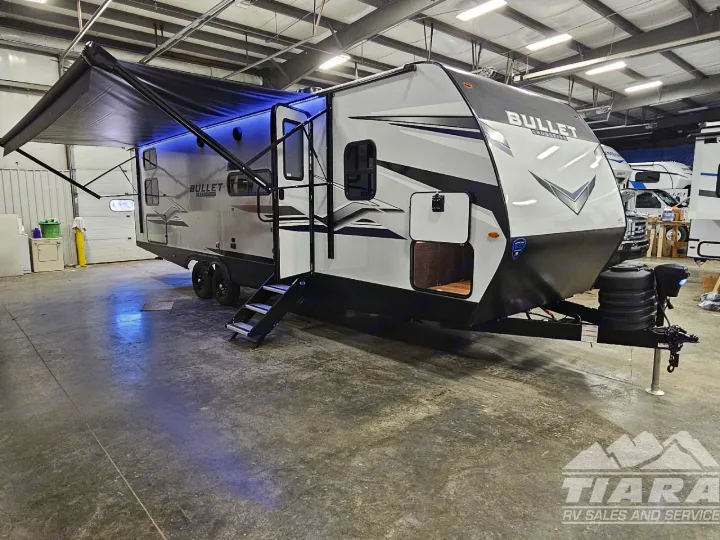 White & black Bullet travel trailer with an extended awning, blue lights, and stairs, ready for your RV rental adventure.. Keystone Bullet 2024