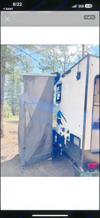 An RV rental with an attached dark grey privacy shower tent, parked in a sunny, wooded campsite. Perfect for outdoor comfort.. Forest River Viking 12000 2024
