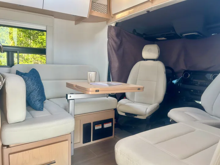 Step inside this modern RV rental! Features light upholstered seating, adjustable dining table, and serene window views.. Leisure Travel Vans Serenity 2022