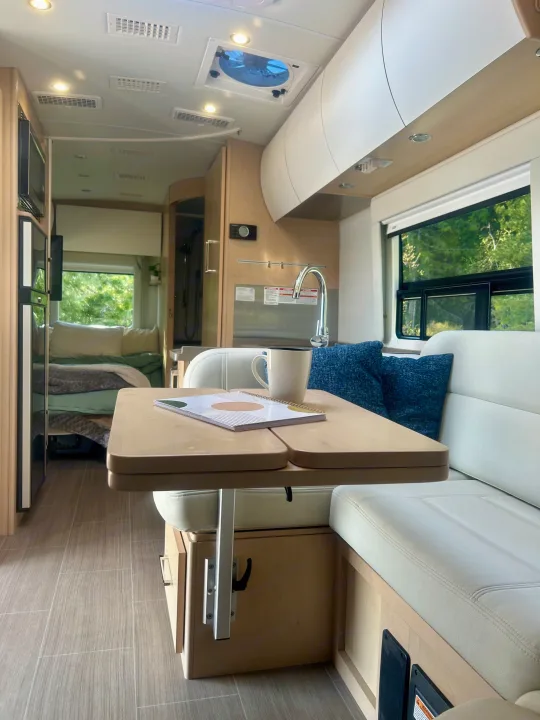 Bright RV rental interior with compact kitchen, flexible dining space, cozy bed, and bathroom.. Leisure Travel Vans Serenity 2022