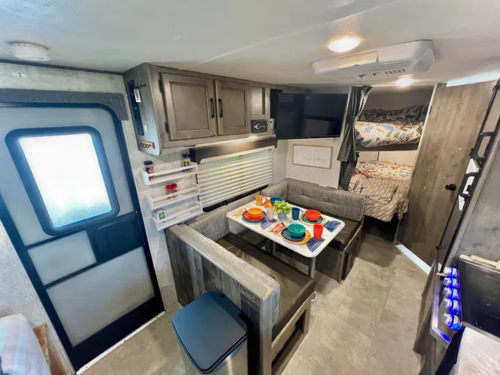 Step into this bright RV rental featuring a cozy dinette with colorful settings, overhead cabinets, TV, and bunk beds.. Coachmen 226 BH 2019