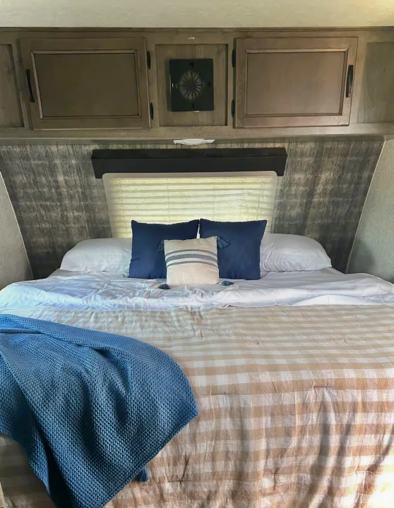 Step into comfort! This RV rental bedroom features blue/beige bedding, overhead storage, and a unique compass fan.. Coachmen 226 BH 2019