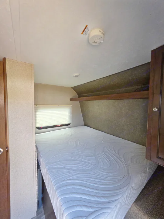 This RV rental offers a compact bedroom with a pristine mattress, window, and essential safety features like a smoke detector.. Keystone RV Hideout LHS Mini 2017