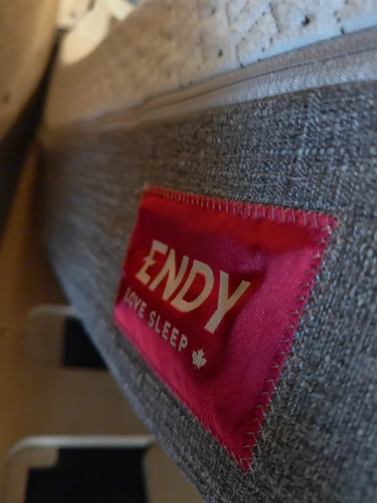 Close-up of a red Endy mattress tag ('LOVE SLEEP', Canadian maple leaf) in an RV rental, ensuring comfy travels.. Mercedes-Benz Sprinter 2017