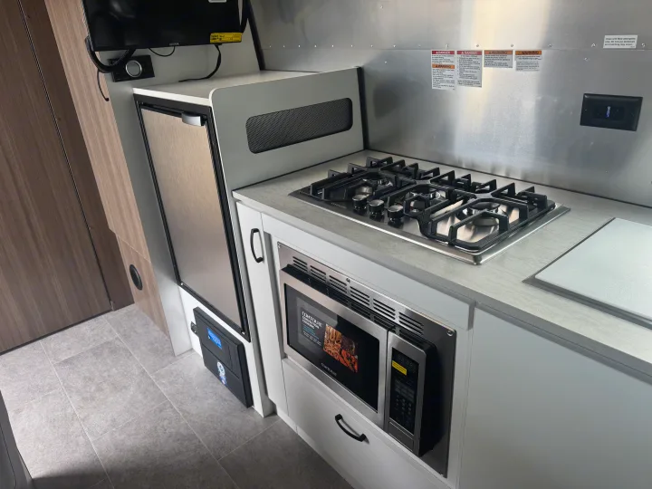 This RV rental features a compact kitchen with a gas stove, microwave, fridge, and ample countertop space for mobile living.. Airstream 22' Airstream Caravel 2025
