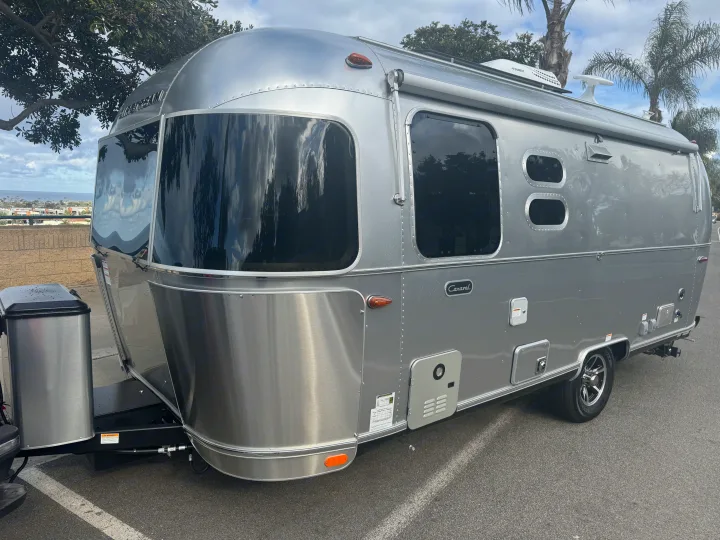 A shiny silver Airstream Caravel travel trailer, ideal for an **RV rental** adventure, parked outdoors with ocean views.. Airstream 22' Airstream Caravel 2025