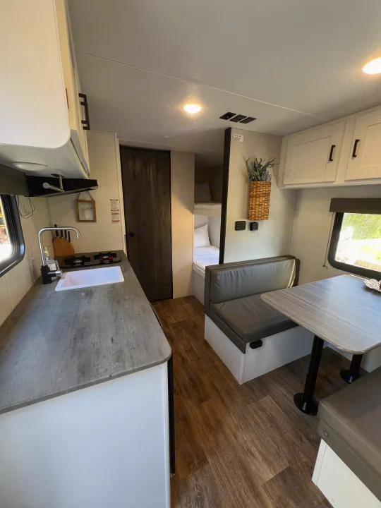 Clean RV rental interior featuring a compact kitchen, comfortable dinette, and cozy bunk beds. Ideal for road trips!. Keystone RV Hideout 2021