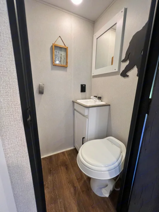 Inside your RV rental: a bright, functional bathroom with sink, toilet, mirror, and unique Bigfoot decor.. Keystone RV Hideout 2021