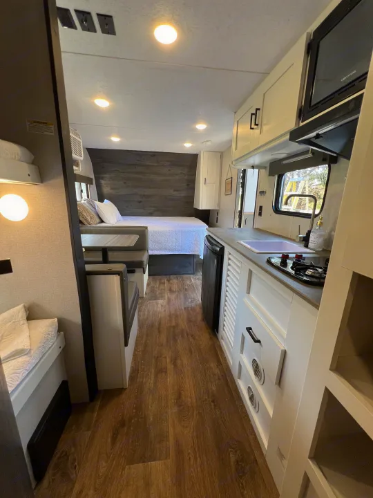 Bright RV rental interior featuring a full kitchen, main bed, dinette, and bunk beds for comfortable travel.. Keystone RV Hideout 2021