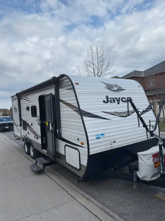 White Jayco travel trailer with steps extended, parked on a street. Explore the open road with an rv rental.. Jayco Jay Flight SLX 2019