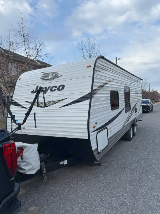 White Jayco travel trailer parked on a residential street, ready for rv rental adventures. Connected to a black truck.. Jayco Jay Flight SLX 2019