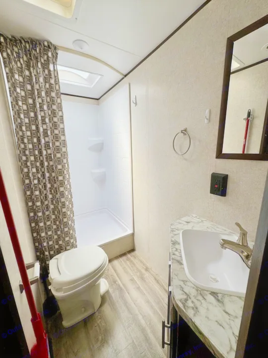 Compact RV rental bathroom featuring a shower, toilet, and sink, with a skylight for natural light.. Jayco Jay Flight SLX 2019