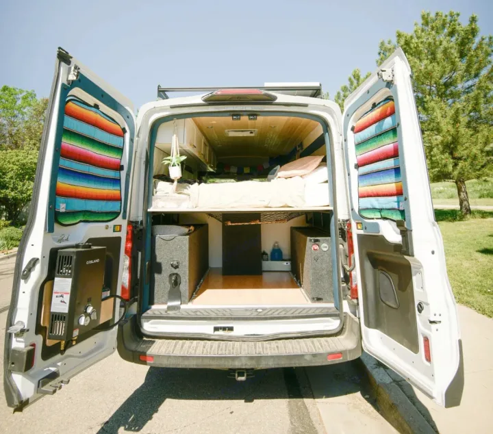 Customized camper van interior, ideal for rv rental adventures. Features a raised bed, under-bed storage, and external water heater.. Ford Transit 2019
