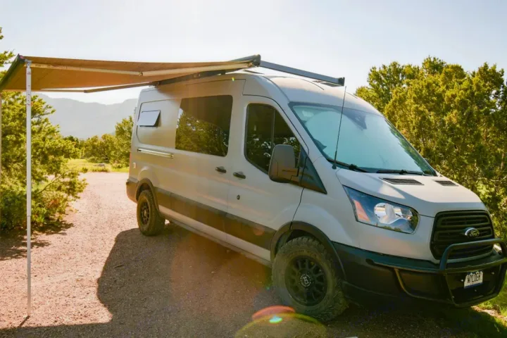 Ready for adventure: a gray Ford Transit camper van RV rental parked outdoors, awning extended for shade.. Ford Transit 2019