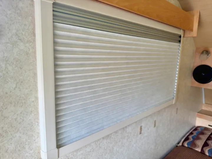 Cozy RV rental interior: a large window with white pleated blinds, light textured walls, and wooden trim.. Pleasant Valley/NuCamp T@B 2016