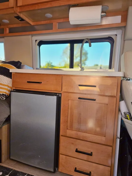 Experience RV rental comfort: a well-appointed kitchenette with sink, fridge, stone counter, and wooden cabinets for your adventures.. Forest River Coachmen Beyond 2023