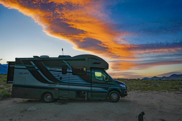 Delano rv rental at sunset under a spectacular orange & blue sky, perfect for desert camping with mountain views.. Thor Delano Sprinter 2020