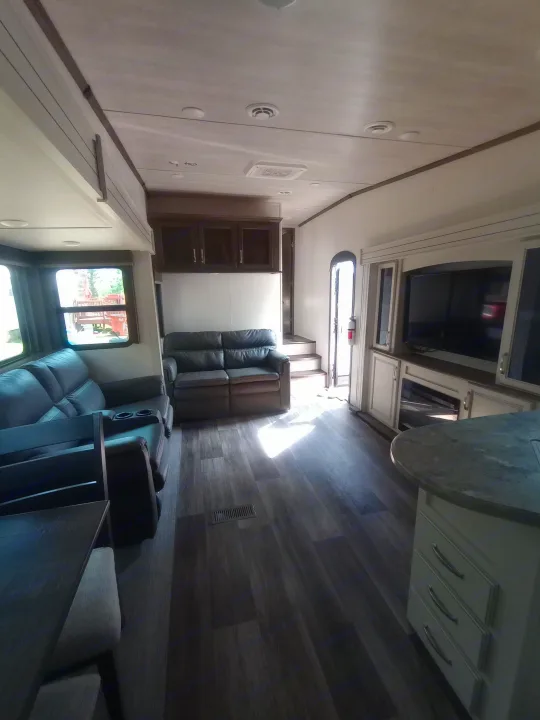 Spacious RV rental interior featuring a modern living area with sofas, TV, kitchen island, and wood-look flooring.. Keystone RV Cougar 2022