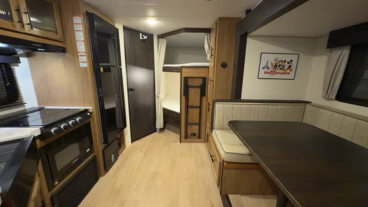 Step inside this inviting RV rental: a modern interior with kitchen, dining booth, and dedicated bunk beds for family comfort.. Forest River Grey Wolf 23DBH 2025