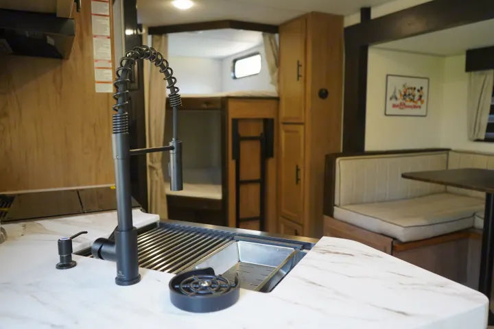 Modern RV rental interior: kitchen, dining, bunk beds. Compact and comfortable living space.. Forest River Grey Wolf 23DBH 2025