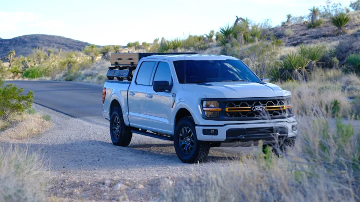 A white Ford F-150 pickup, loaded with overland gear, parked off-road in a desert landscape. Perfect for an rv rental adventure.. Ford Roofnest 2024