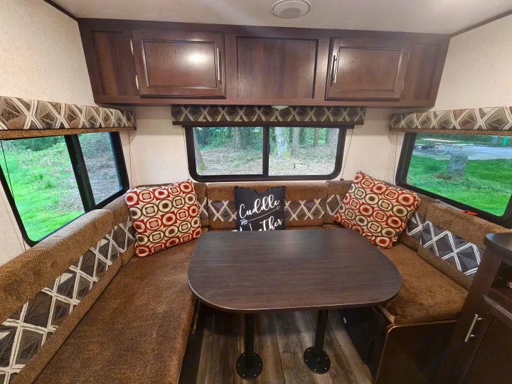 This RV rental features a spacious dinette with U-shaped seating, a table, overhead storage, and scenic windows.. Jayco Jay Flight SLX 2019