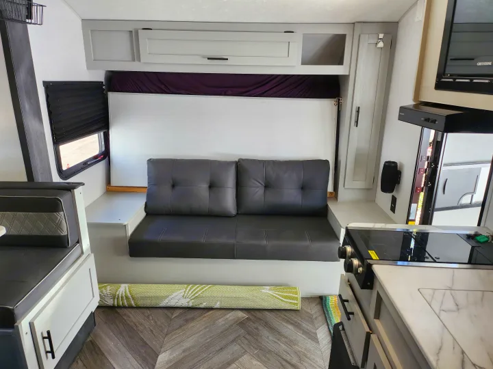 Spacious RV rental interior with a convertible sofa-bed, dinette, and well-equipped kitchen area.. Forest River Wildwood FSX 2022