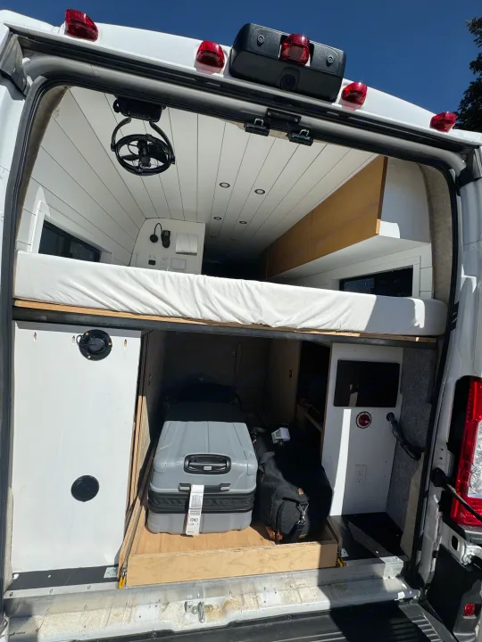 Inside a custom RV rental, this camper van features a bed, overhead fan & lights, plus ample rear pull-out storage.. Custom Ram Promaster 2021