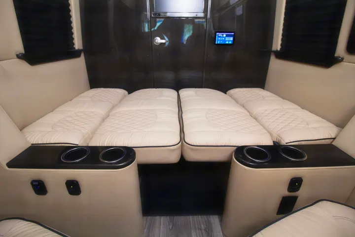 Luxury **RV rental** interior with plush, convertible seating/beds, charging ports, & cup holders for ultimate travel comfort.. Ultimate Toys Ultimate Commuter 144 2022