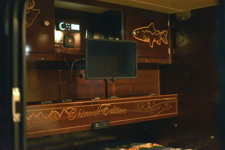 RV rental's custom wood interior: "Chinook Edition" etched panel, nature art (deer, fish), display, and keypad.. Teardrops NW Ranger 2025