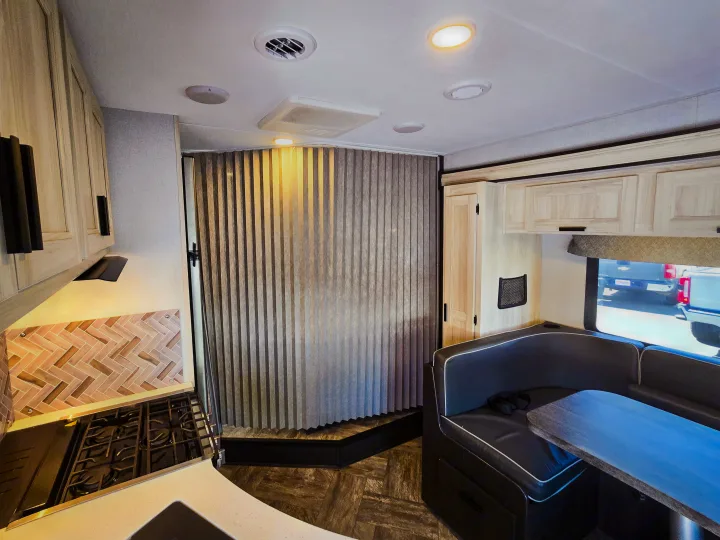 Modern RV rental interior with a bright kitchen, cozy dinette booth, and accordion partition. Perfect for adventures.. Forester Classic 2022
