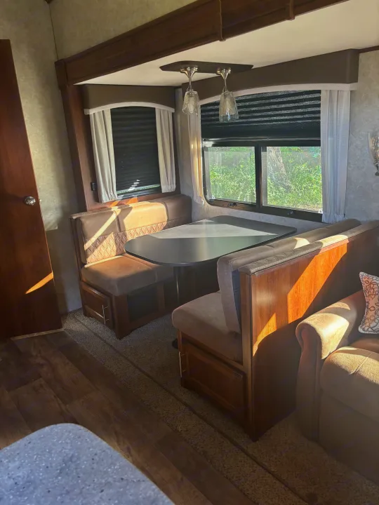 Cozy RV rental interior featuring a dinette booth, sofa, and sunny windows, perfect for travel comfort.. Jayco Eagle HT 2018