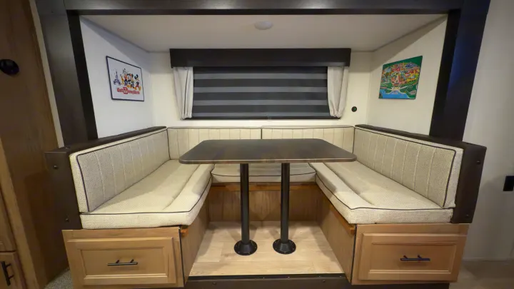 RV rental interior featuring a cozy dinette booth with a table and built-in storage, perfect for dining or relaxing.. Forest River Grey Wolf 23DBH 2025