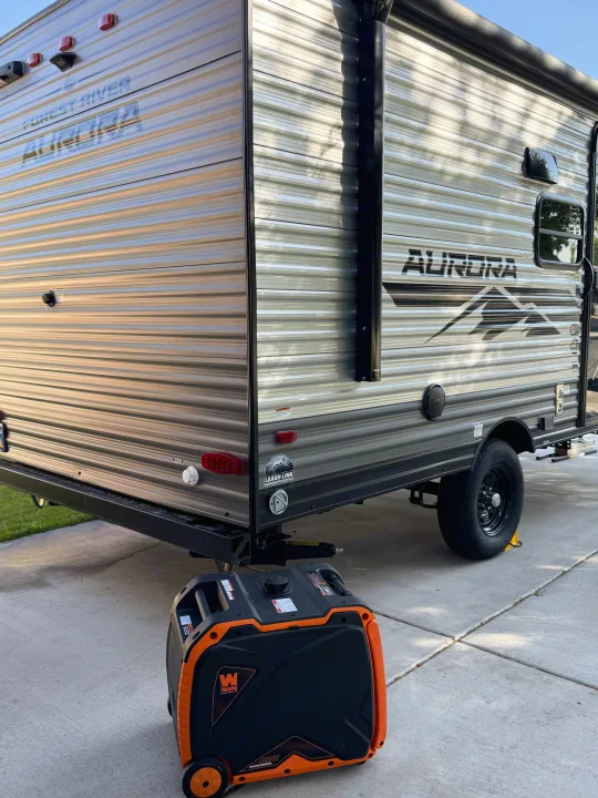 Forest River Aurora travel trailer for rv rental, parked on concrete with a WEN inverter generator.. Forest river Aurora light 16BHX 2025