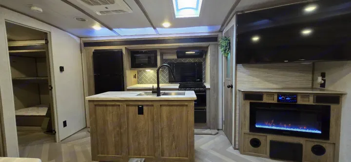 Modern RV rental interior: kitchen island, fridge, stove, microwave, TV, fireplace, and bunk beds visible. Spacious camper.. Forest River Salem Hemisphere 2021