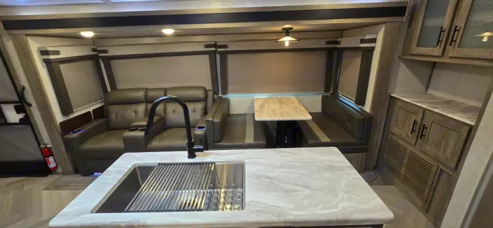 Spacious RV rental interior: A modern kitchen area with sink, comfortable recliners, and a cozy dinette booth.. Forest River Salem Hemisphere 2021