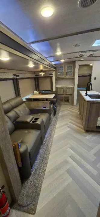 Spacious RV rental interior featuring comfortable recliners, a dining booth, and a full kitchen with herringbone flooring.. Forest River Salem Hemisphere 2021