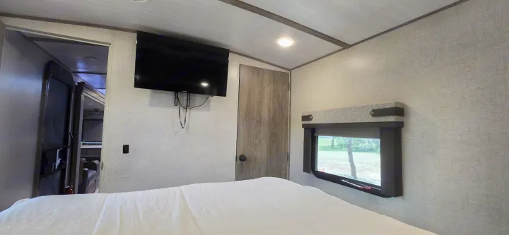 Spacious RV rental bedroom with a comfy bed, wall-mounted TV, and window offering outdoor views.. Forest River Salem Hemisphere 2021