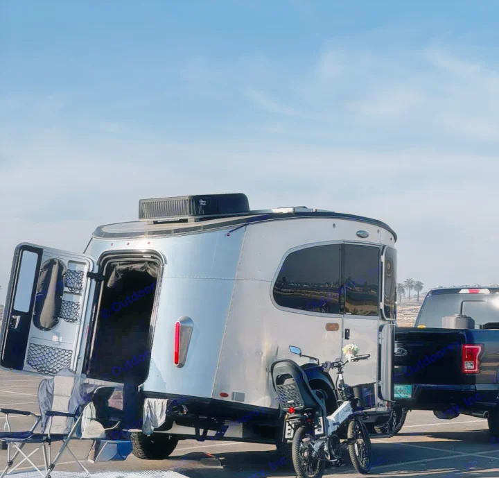 This modern silver RV rental, towed by a pickup, is ready for adventure with an e-bike & camping setup. Perfect for outdoor trips.. Airstream Basecamp 2021