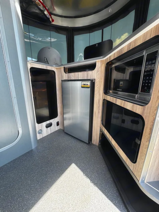 Compact RV rental kitchenette featuring microwave, mini-fridge, and storage. Ideal for efficient on-the-go living.. Airstream Basecamp 2021