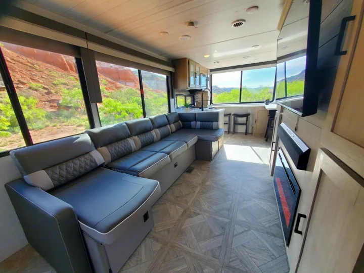 Modern RV rental interior with a spacious L-shaped sofa, full kitchen, and stunning views of the red rock landscape.. Forest River Salem Platinum 2024