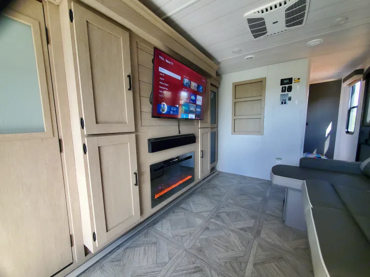 Modern RV rental interior with a large TV, electric fireplace, wood-look cabinets, and comfortable seating for a cozy stay.. Forest River Salem Platinum 2024