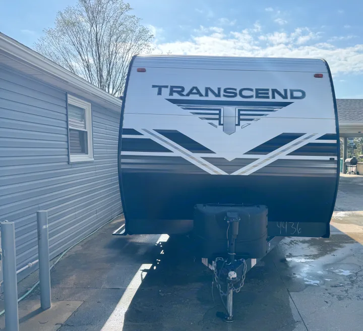 Front of a Transcend travel trailer, an ideal rv rental, parked by a blue house on a sunny day.. Grand Design Transcend Xplor 2020