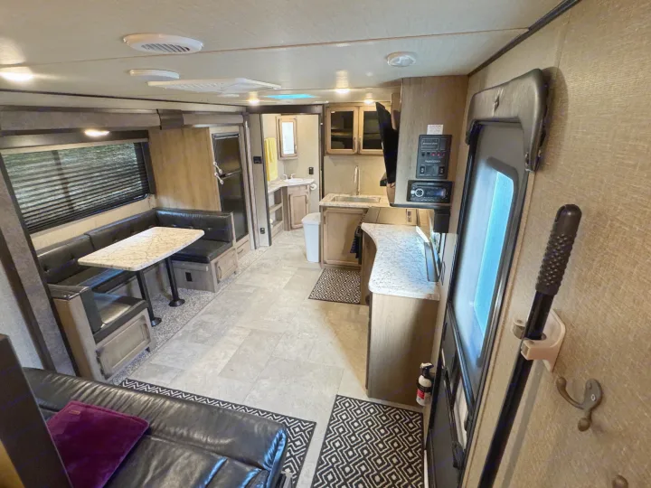 Explore this RV rental's well-appointed interior: dinette, kitchen, and bathroom visible, providing a cozy mobile living space.. Grand Design Transcend Xplor 2020