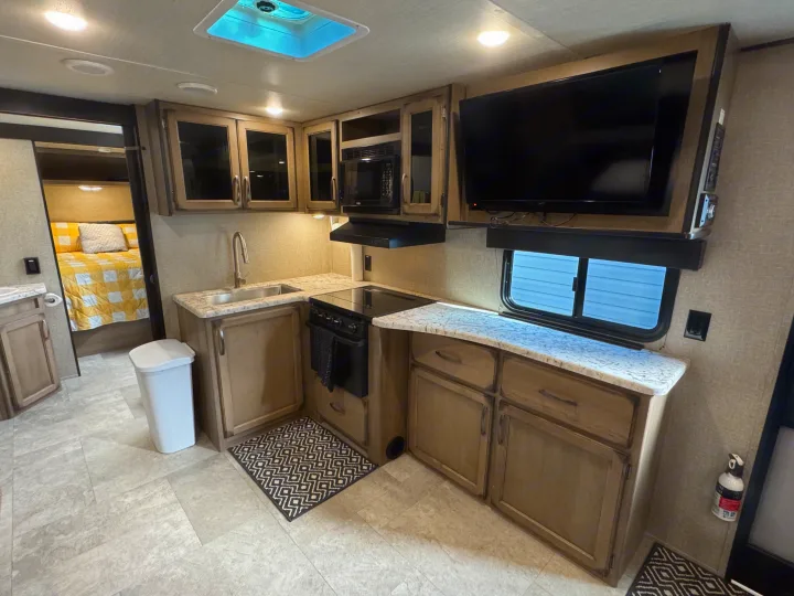 Modern RV rental interior featuring a full kitchen, TV in living area, and bright bedroom. Your ideal travel home.. Grand Design Transcend Xplor 2020