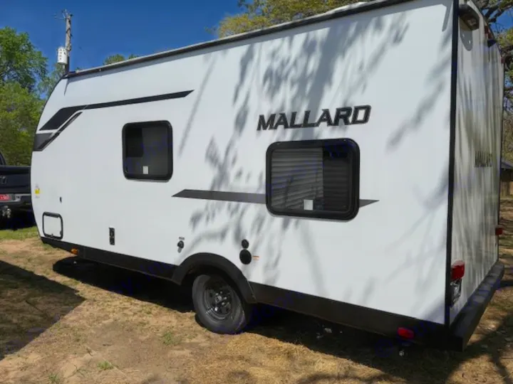 White Mallard travel trailer with black accents and windows, parked outdoors. An excellent RV rental option.. Heartland Mallard Mallard 2025